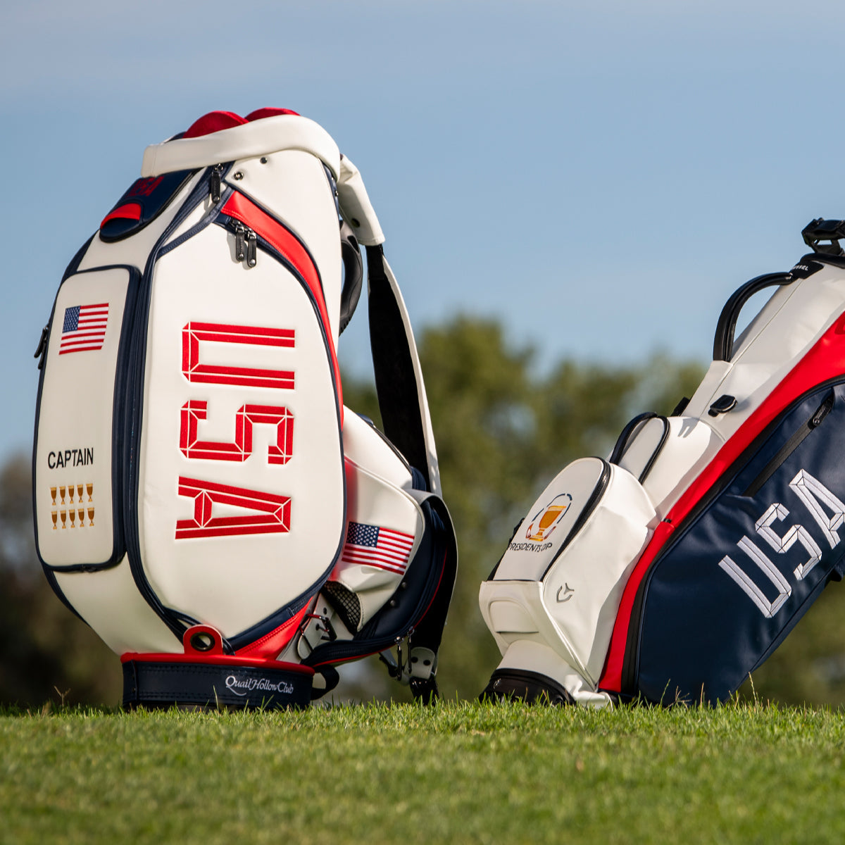 Two VESSEL golf bags made for the USA Presidents Cup team on a golf course: a white captain's staff bag with red USA lettering and a red, white and navy stand bag